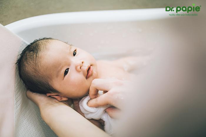 Khi tắm cho trẻ, mẹ quấn khăn quanh người để giữ ấm trong cả quá trình vệ sinh. 